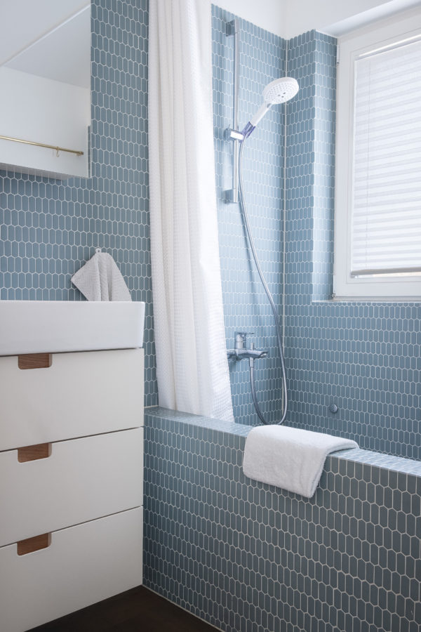 Salle de bains avec des carreaux hexagonaux bleus et un meuble de salle de bains blanc.
