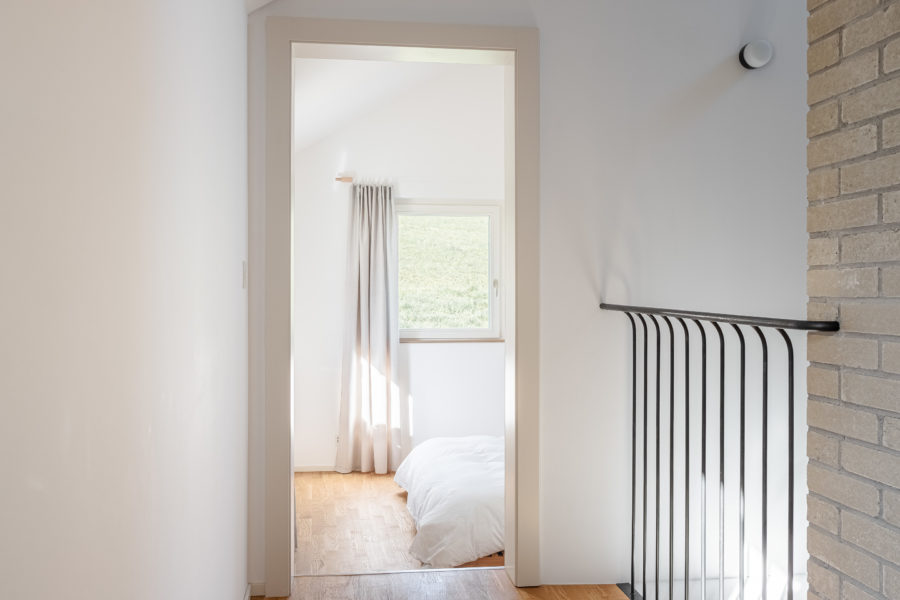 Chambre avec lumière naturelle et garde corp d’escalier en métal à droite.
